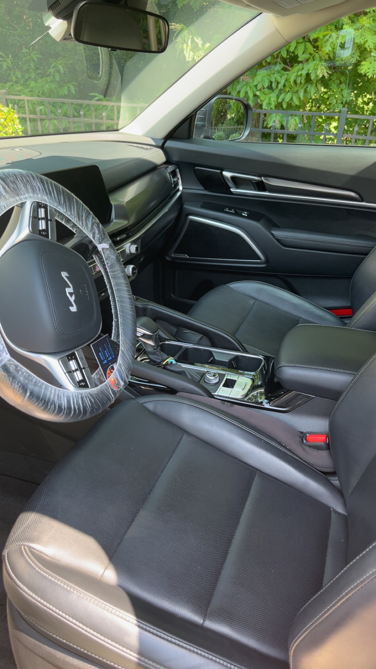 Kia front interior mid-detail with a protective wrap still on the steering wheel