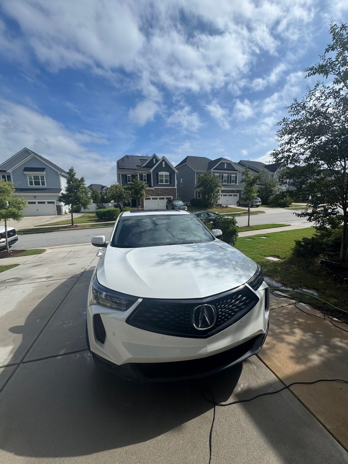 Freshly washed white Acura SUV parked in a driveway